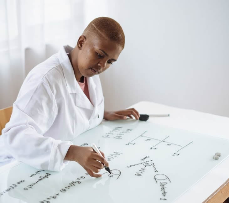 Focused African American teenage chemist working on formula in scientific center